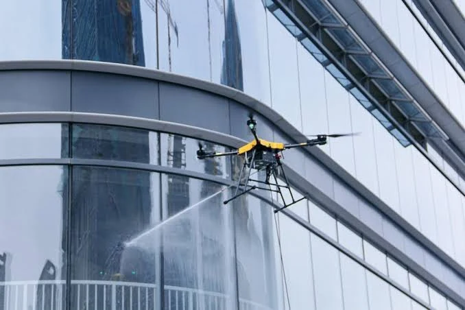 Drone washing a glass curtain-wall facade on a high-rise