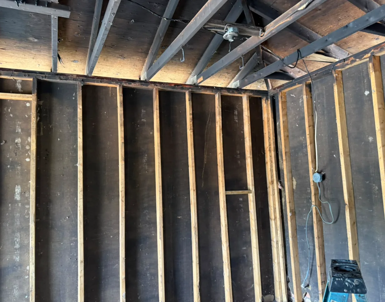 Garage interior before dry ice blasting, walls and roof structure blackened with char and soot after a house fire