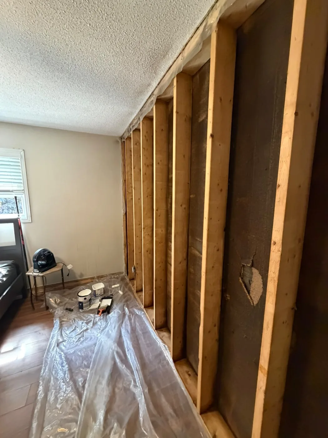 Bedroom wall studs cleaned back to bright grain by dry ice blasting, with fire-darkened sheathing behind them