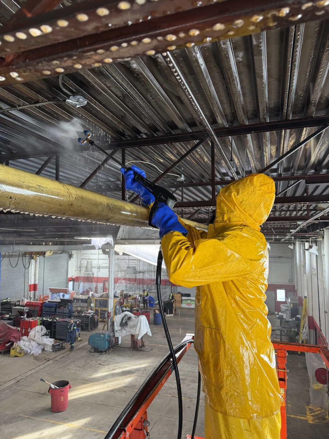 Pure Blast Solutions technician pressure washing an overhead steel roof deck inside a commercial facility in the GTA
