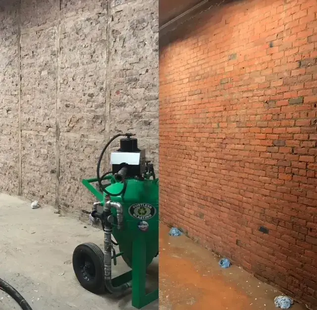 Dustless sandblasting rig stripping a commercial brick wall