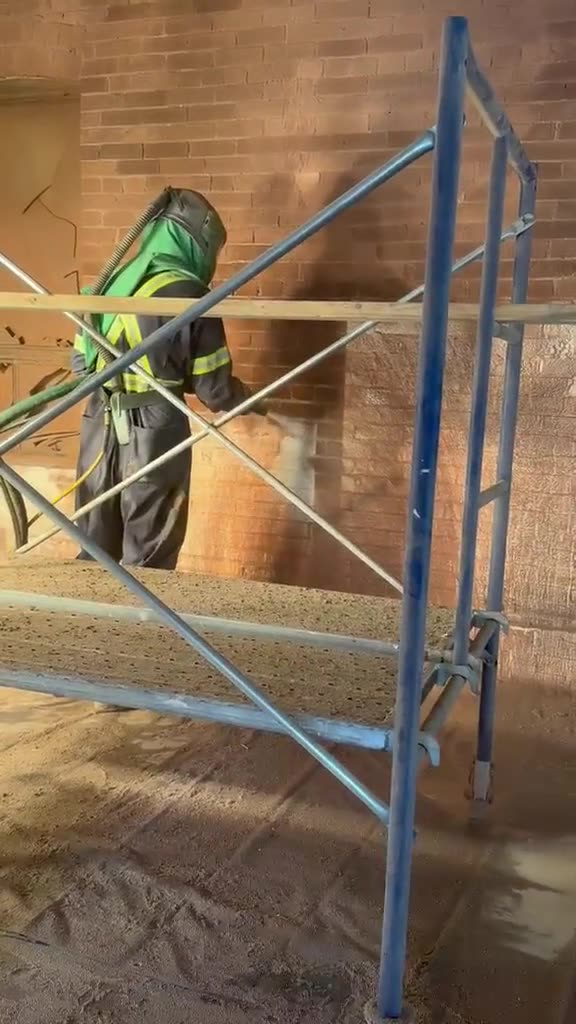 Technician sandblasting heritage brick from a scaffold